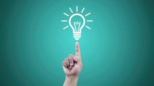 A hand points at a light bulb, symbolizing innovative small business ideas.